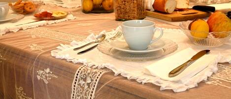 A breakfast table set with various food items, including fruits, bread, and a cup.