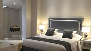 A modern hotel room with a large bed, two bedside tables with lamps, a small desk, and a chair. - La Villetta Suite (Ciampino)