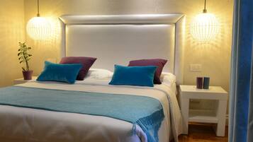 A neatly made bed with a white headboard, two bedside tables, and a potted plant on the left.