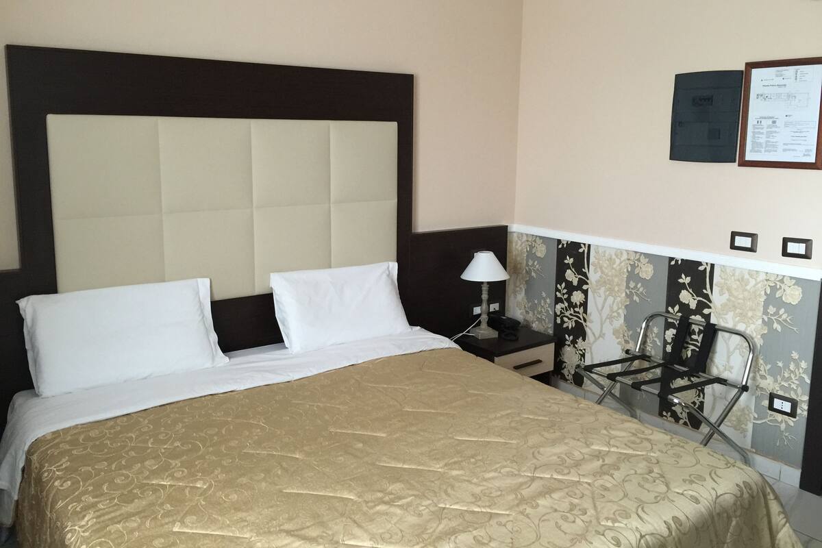 Ein Hotelzimmer mit einem großen Bett, einem Nachttisch, einer Lampe und einem Sessel.