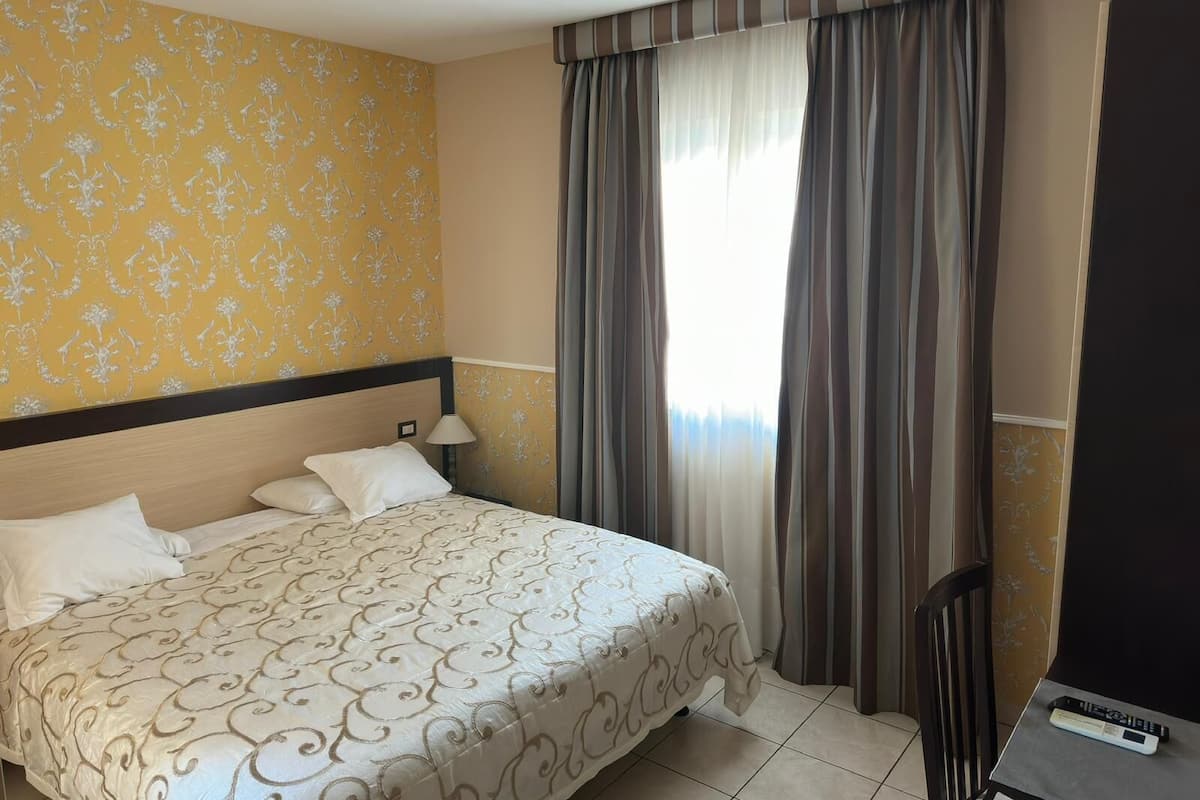 Ein Hotelzimmer mit Bett, Schreibtisch und Stuhl.