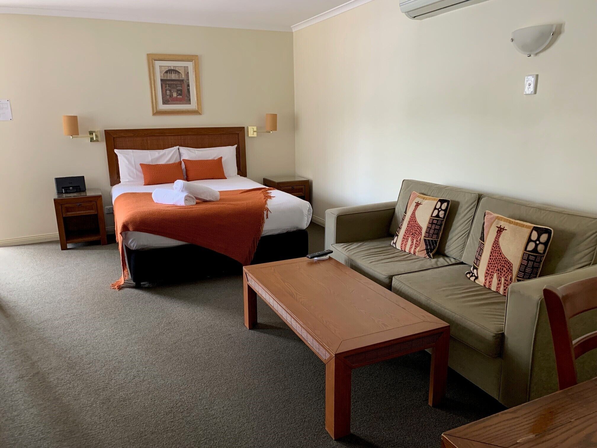 Une chambre d’hôtel avec un lit, un canapé, une table en bois et un climatiseur fixé au mur.
