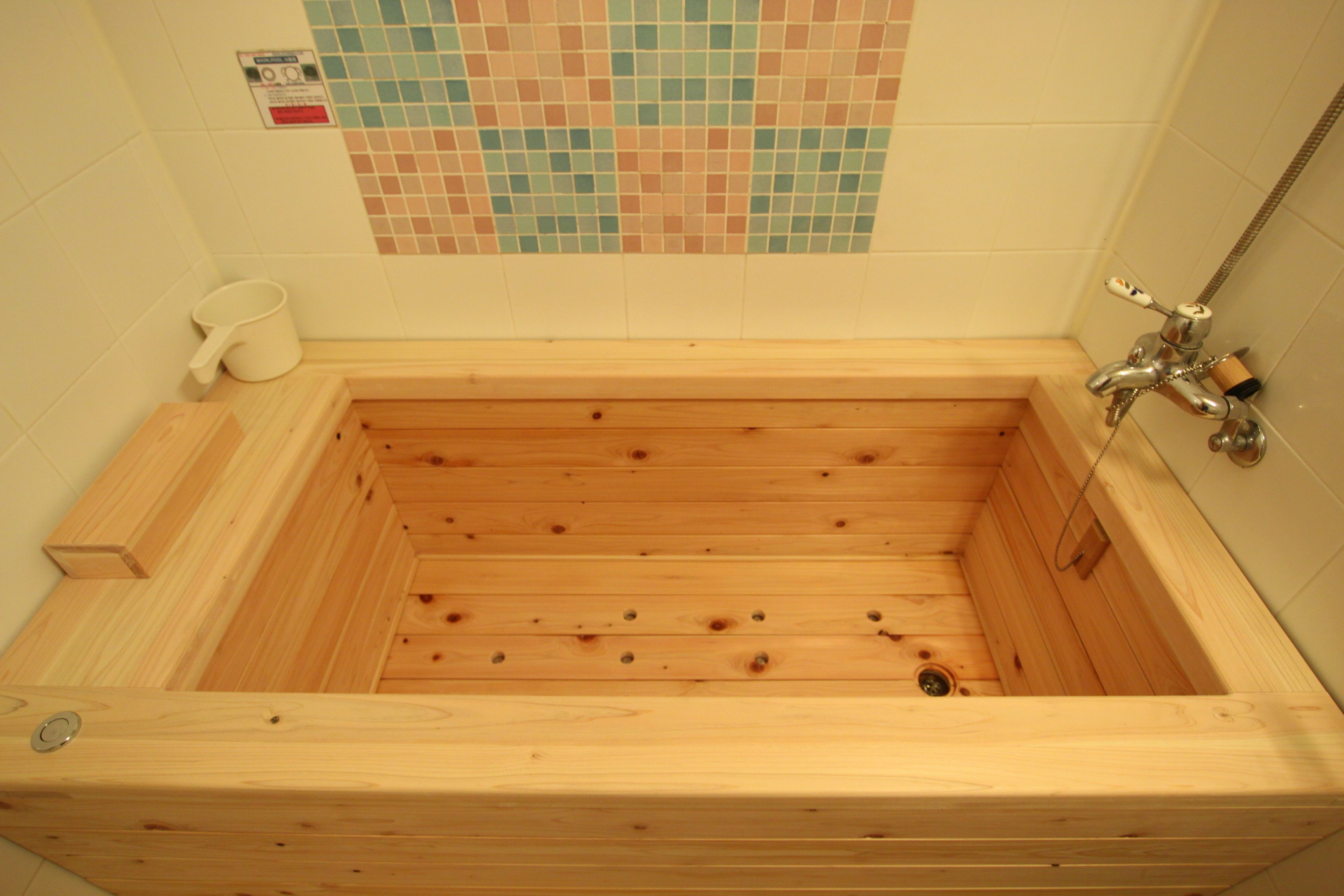 Una bañera de madera con un muro cubierto de mosaicos de cerámica.