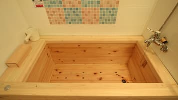 Una bañera de madera con un muro cubierto de mosaicos de cerámica.