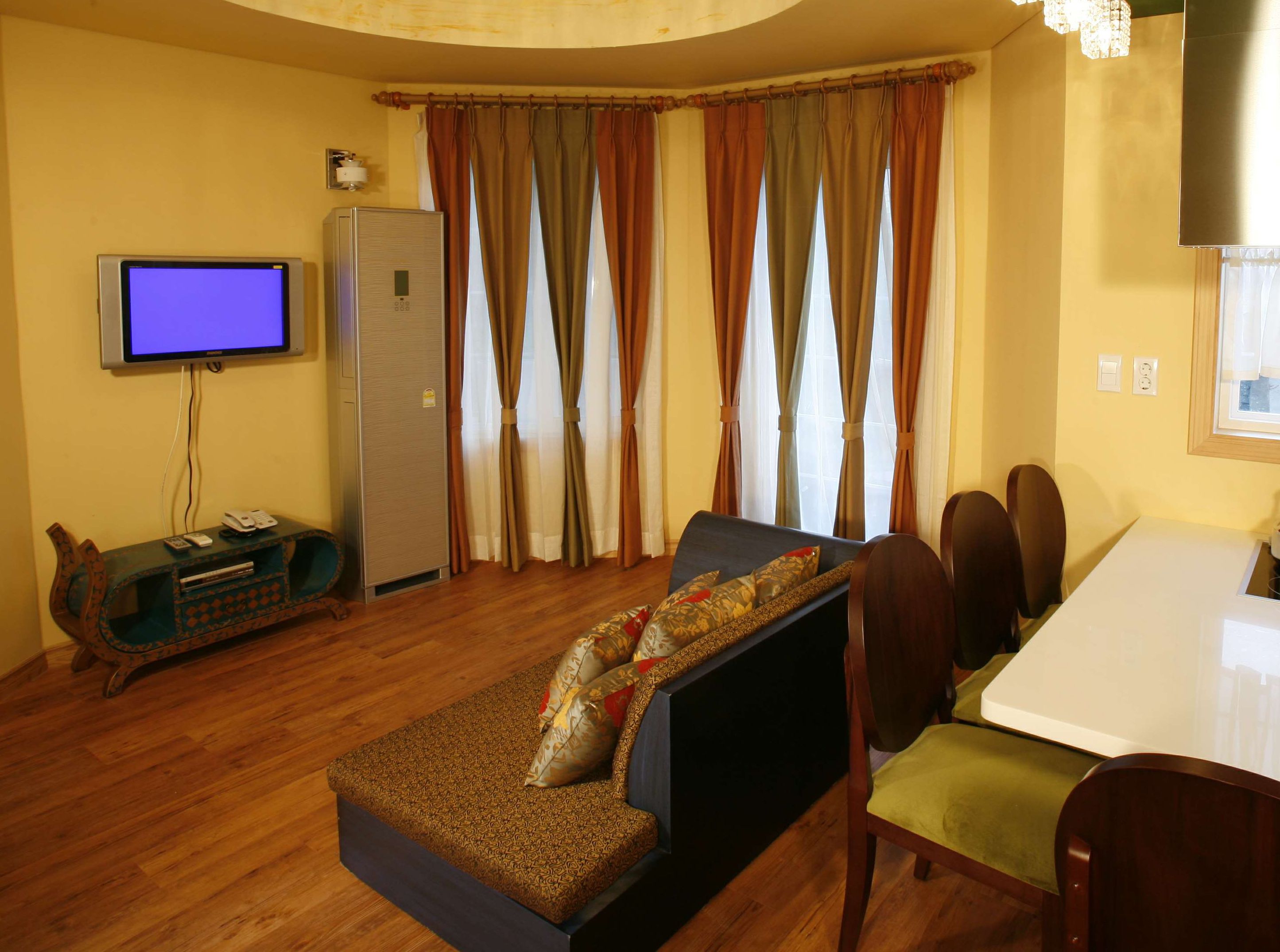 A living room with a sofa, TV, refrigerator, and dining area.