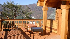 A wooden deck with a table and chairs, overlooking a mountainous landscape.