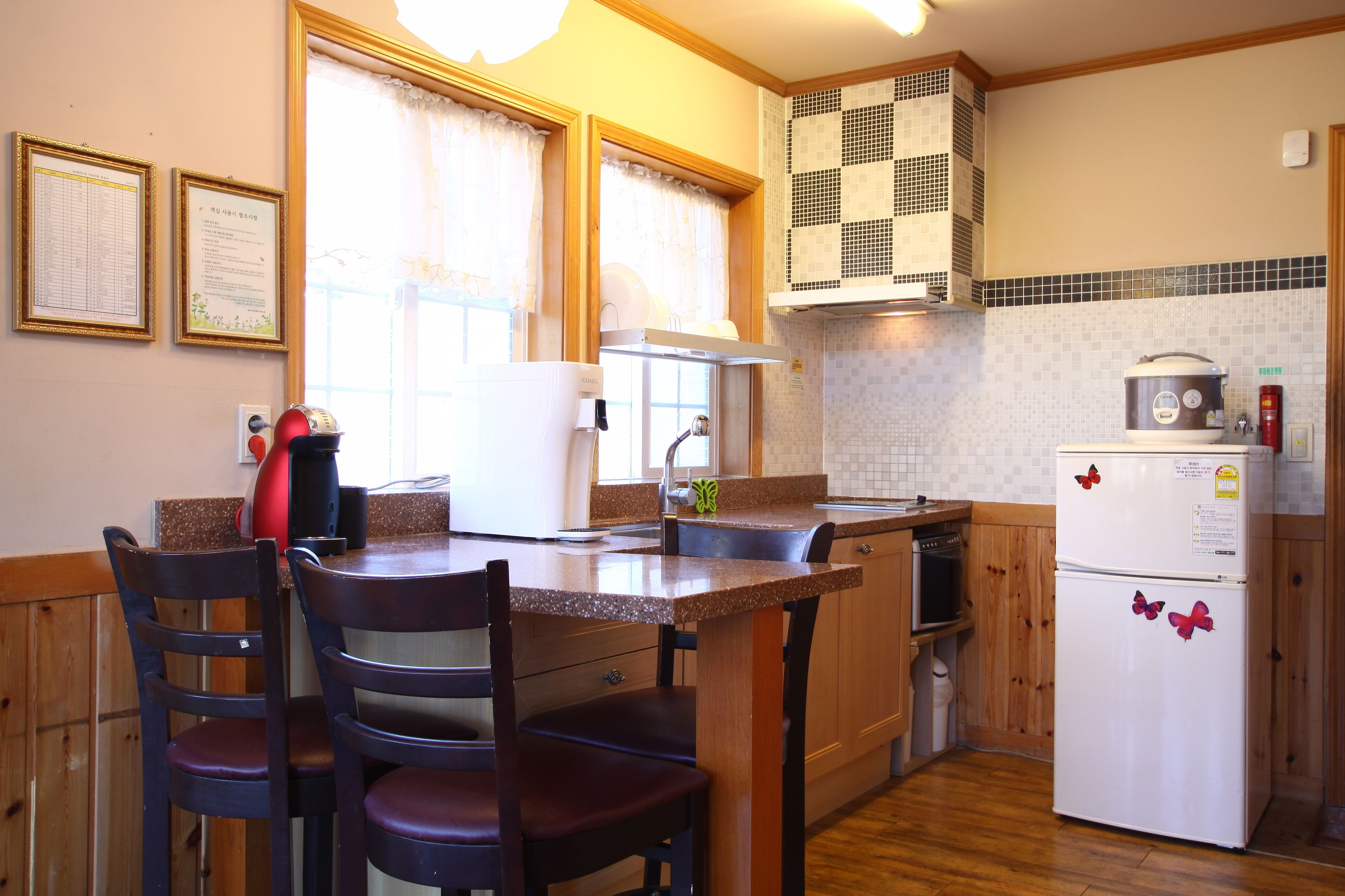 Una cocina con armarios de madera, un refrigerador, una estufa y un comedor con sillas.