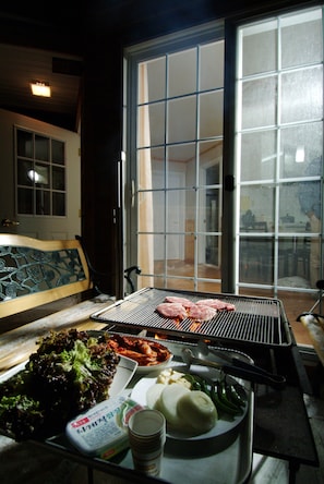 A dining area with a grill, a bench, and a table with food and drinks. - Elf Resort Hotel (Pyeongchang)