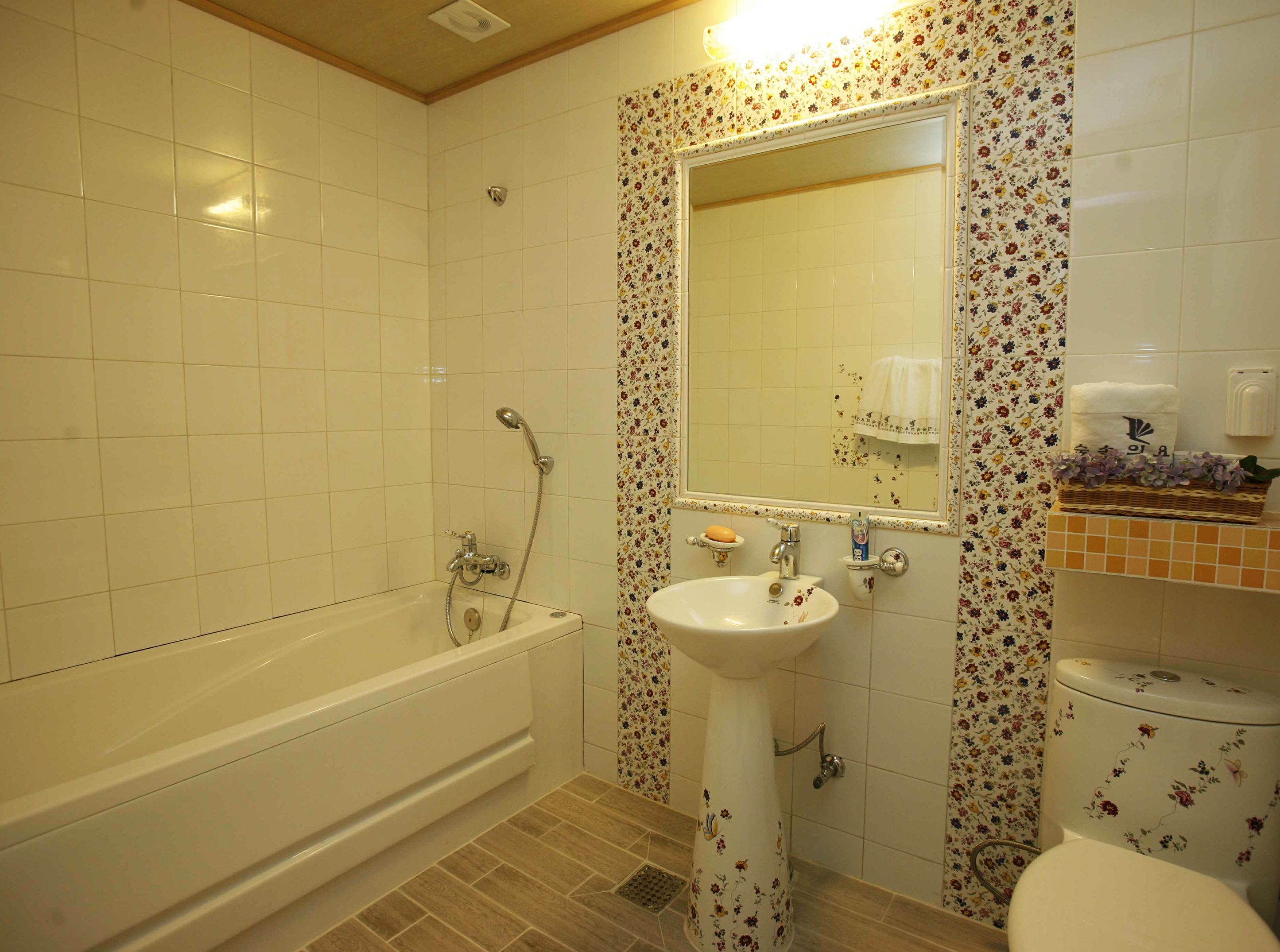 A bathroom with a bathtub, sink, and toilet, all with floral tile borders.