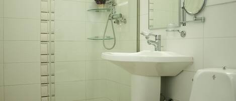 A bathroom with a glass shower enclosure, a white sink, and a toilet.