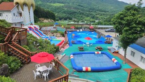 A pool area with slides, a small inflatable pool, and picnic tables.