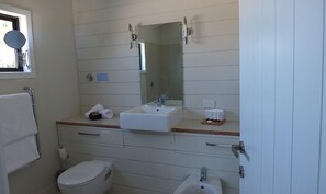 Ein Badezimmer mit einem weißen Waschbecken, einem Spiegel, einer Toilette und einem Bidet.