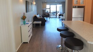 A modern kitchen with a bar area, a dining table, and a living area with a sofa and chairs.