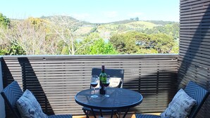 A patio with a round table, two chairs, and a bottle of wine.
