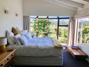 Relax in a serene setting with a large bed and a view of the lush landscape.