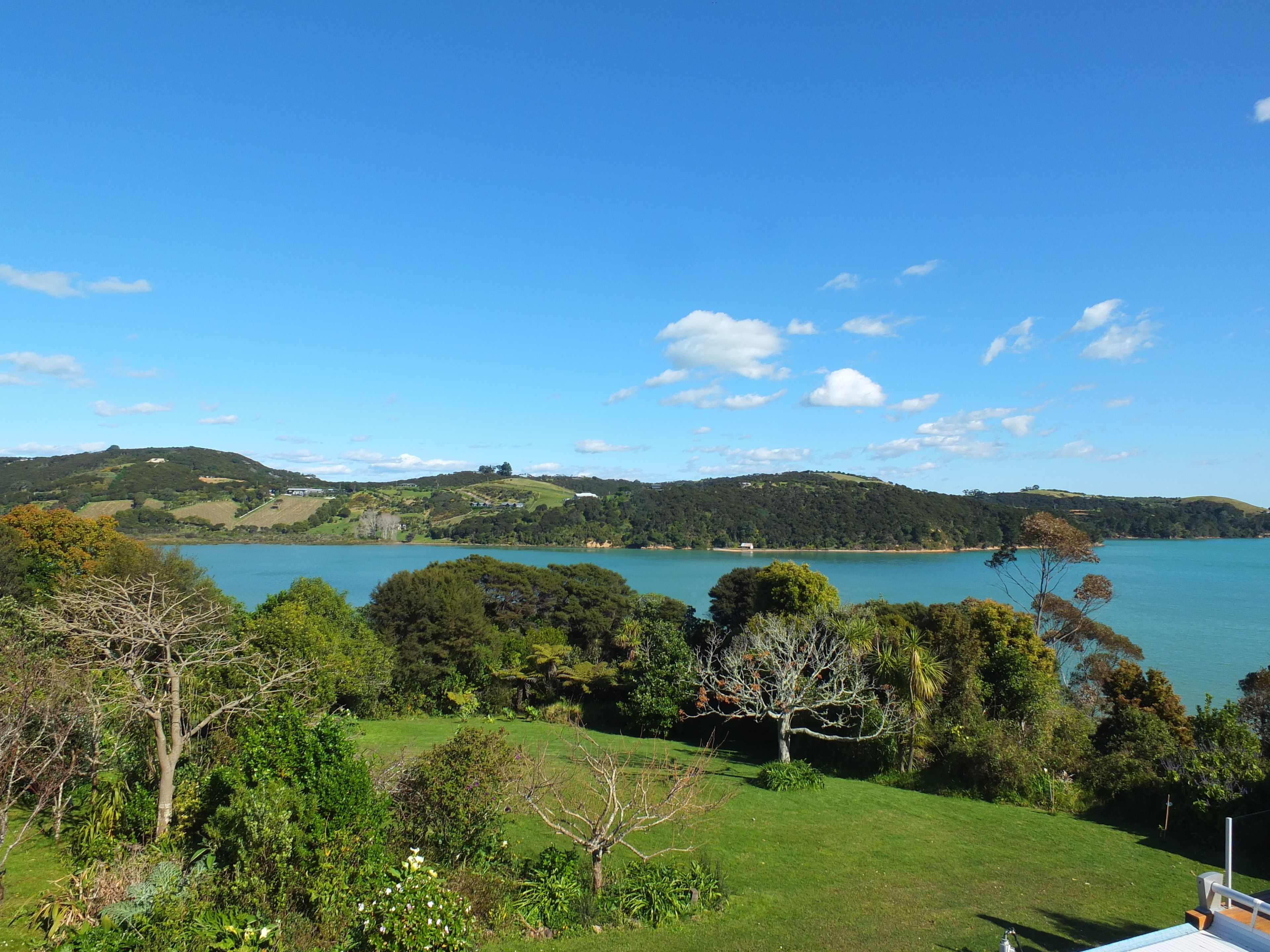 Un paisaje costero con un lago, colinas y diversos árboles.