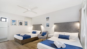 A hotel room with two beds, a ceiling fan, and framed pictures on the wall. - Beach House Motel (North Ward)
