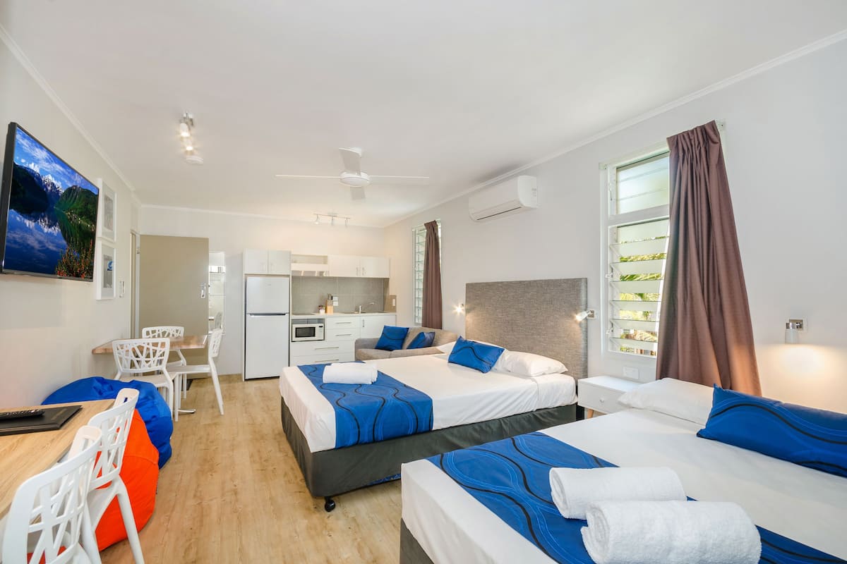 Une chambre d’hôtel avec deux lits, un bureau et une kitchenette.