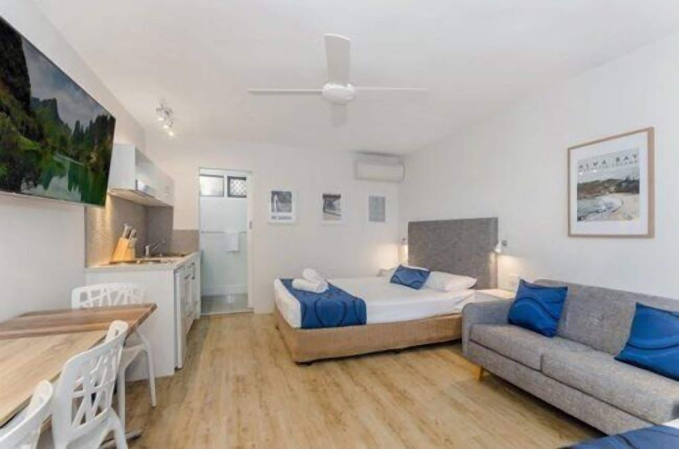 Une chambre d’hôtel de taille réduite, comprenant un lit, un canapé, un bureau et une kitchenette.