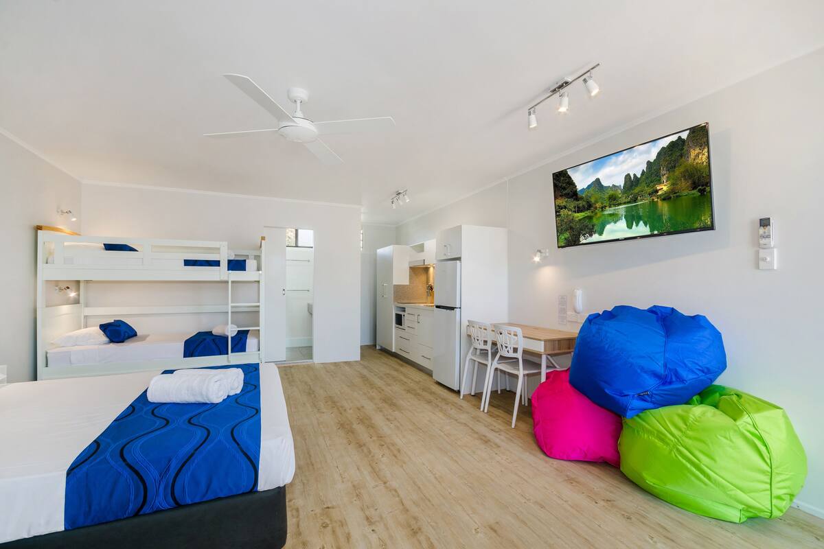 Une chambre d’hôtel moderne équipée d’un lit superposé, d’un bureau, d’une chaise et de fauteuils en forme de sac.