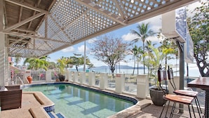 A pool area with a covered seating area, a bar, and a view of the ocean. - Beach House Motel (North Ward)