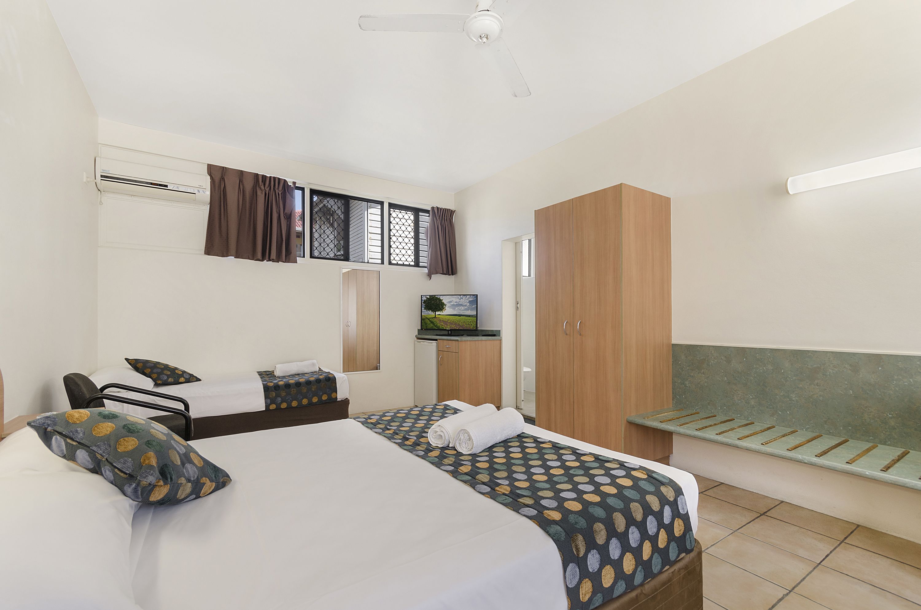 A hotel room with a bed, a desk, a wardrobe, and a TV.