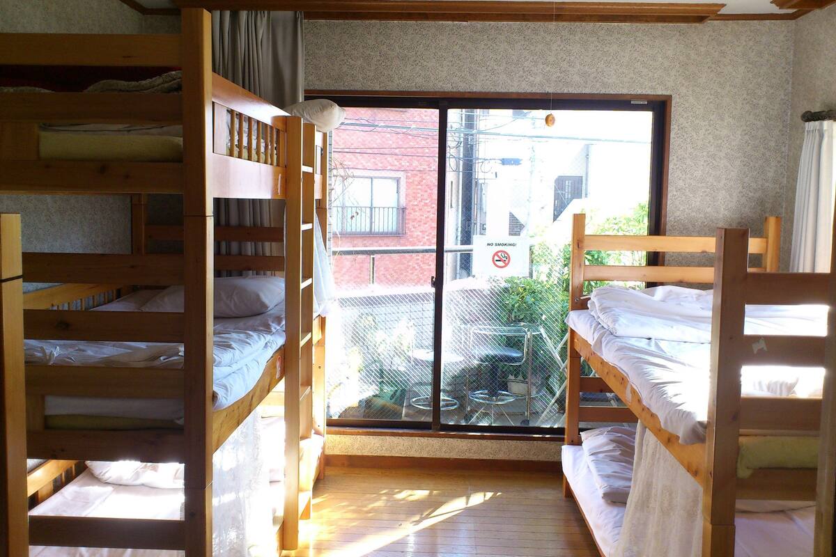 A room with bunk beds, a sliding glass door to the outside, and a 'No Smoking' sign.