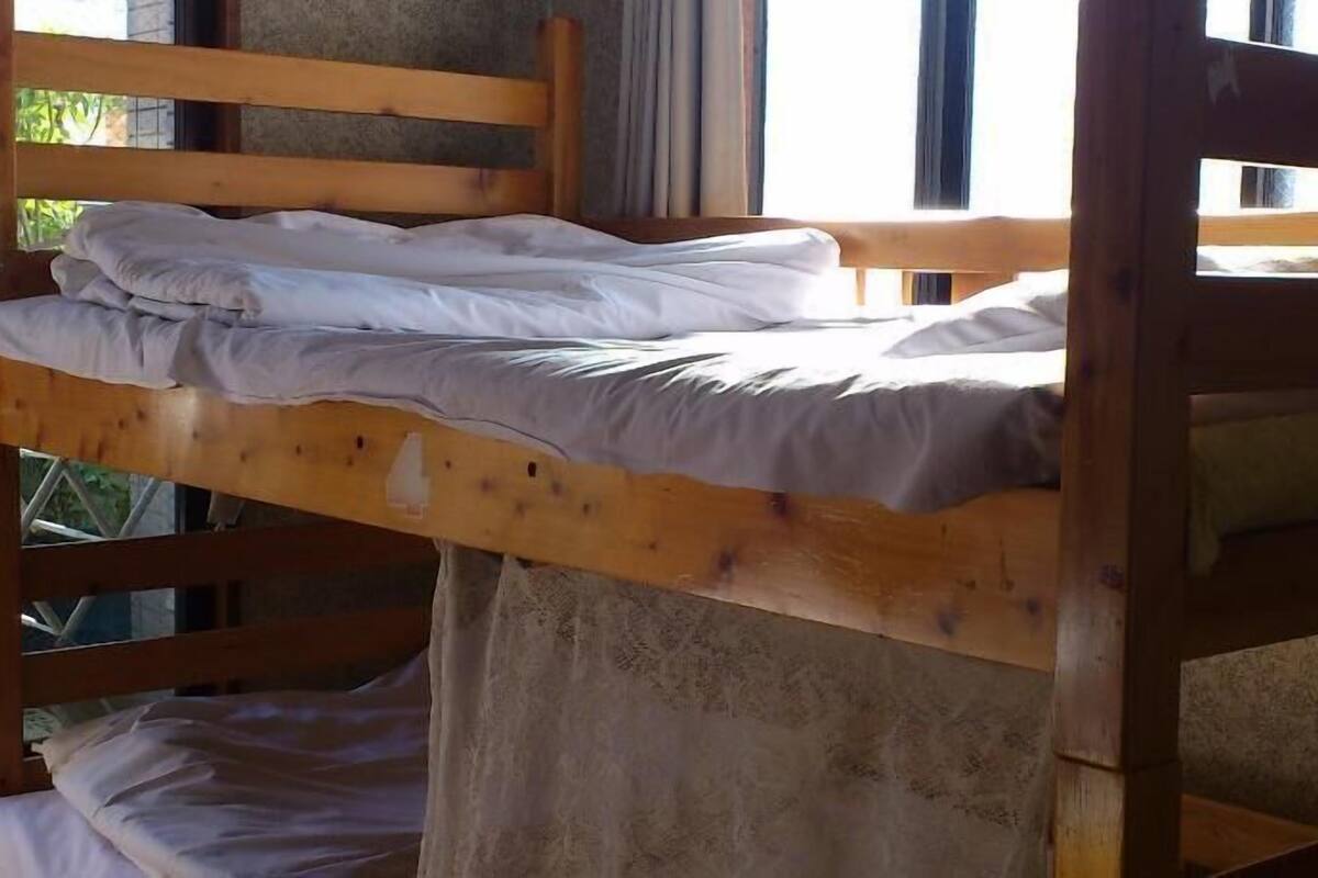 A bunk bed with white bedding and a wooden frame.