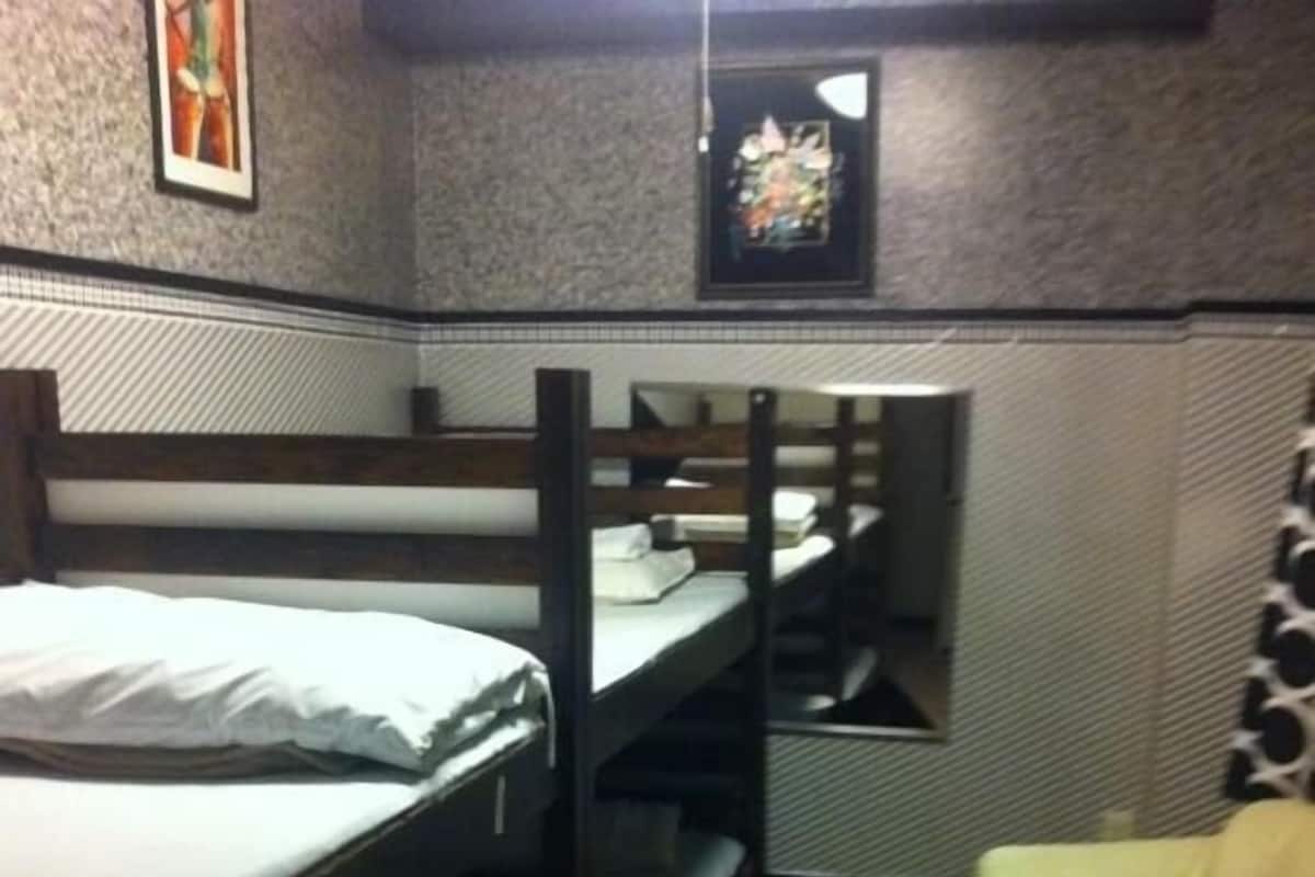 A bunk bed room with a patterned carpet, a small sofa, and artwork on the walls.