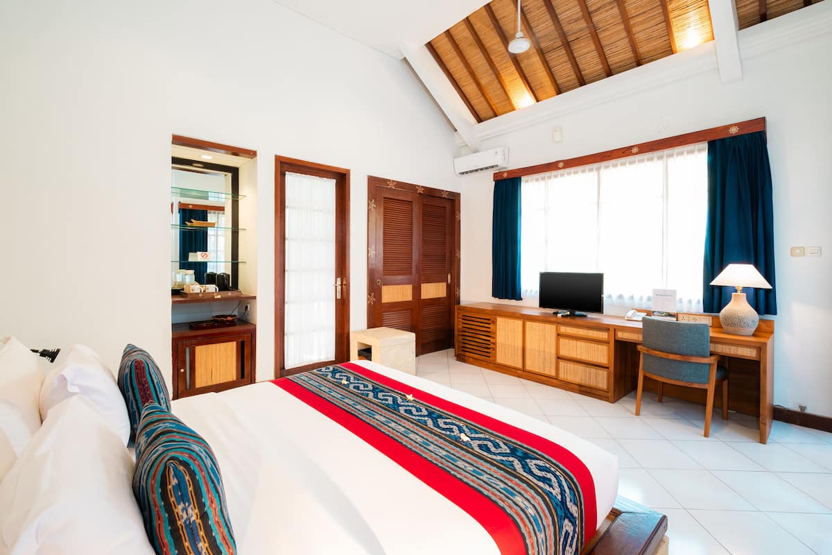 A hotel room with a large bed, a desk, a television, and a window with curtains.