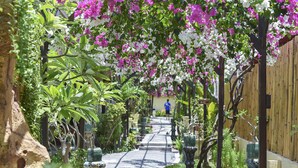 A pathway lined with potted plants and flowering vines, leading to a wooden fence. - Villa Almarik (Gili Trawangan)
