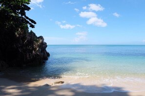 A beach with clear turquoise water, a sandy shore, and rocky cliffs. - Bounty Resort (Ko Pha-ngan)