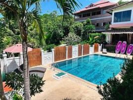 Una piscina al aire libre, sombrillas, sillones reclinables de piscina