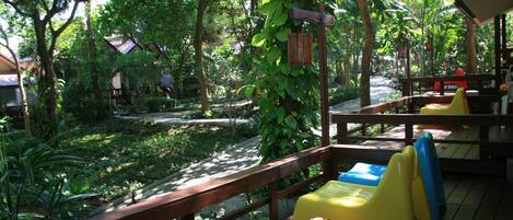 A wooden deck with a view of a garden and a pathway.