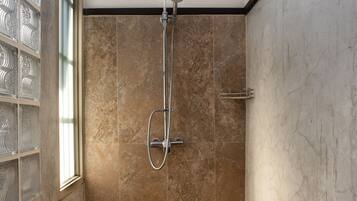 A shower with a glass door, a skylight, and a tiled floor.