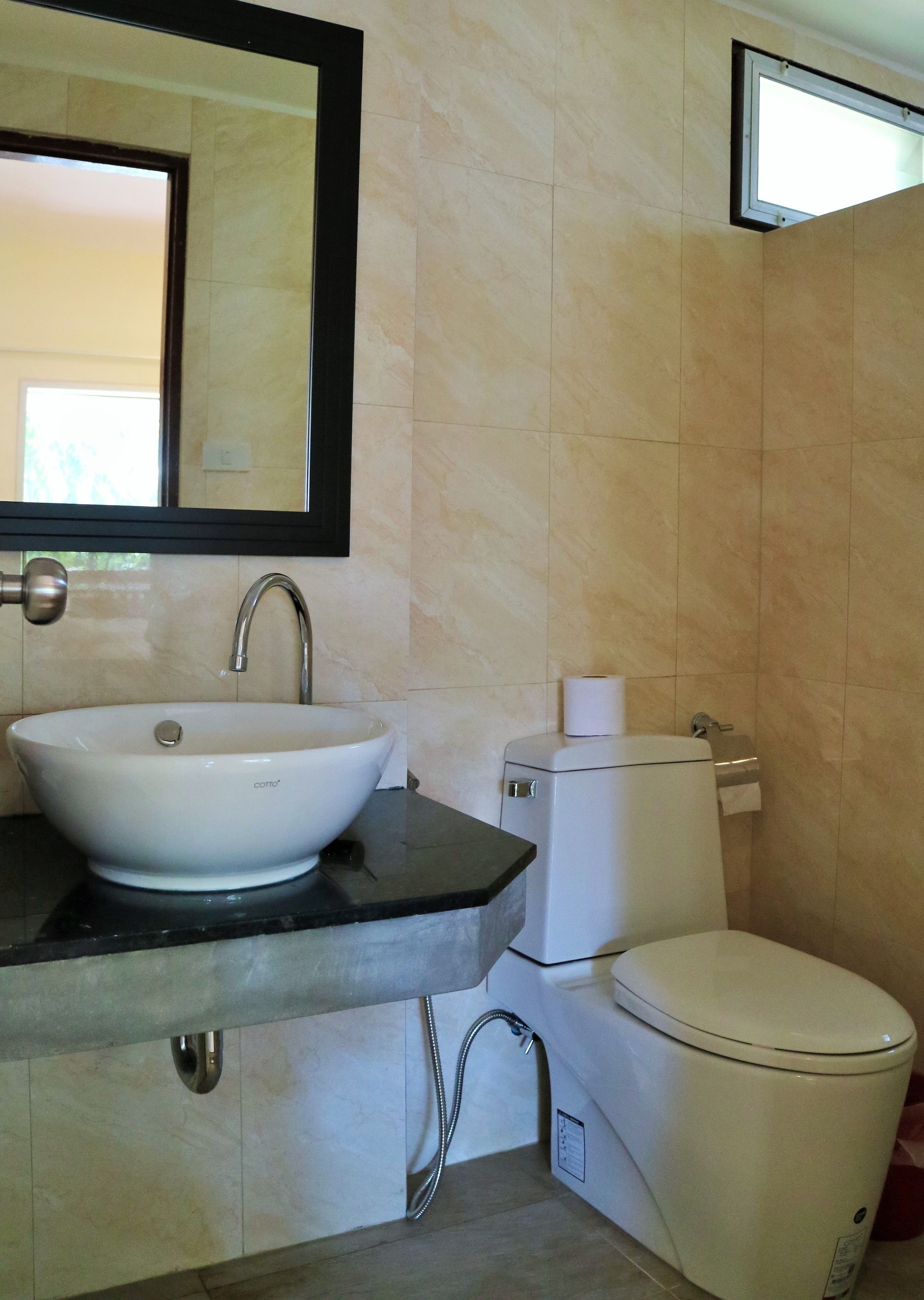 Un baño con un lavabo blanco, un inodoro y un espejo sobre el lavabo.