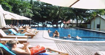 Una piscina al aire libre, sombrillas, sillones reclinables de piscina