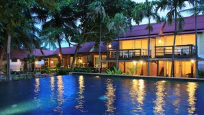 A resort with a swimming pool, multiple guest rooms, and a covered outdoor area.