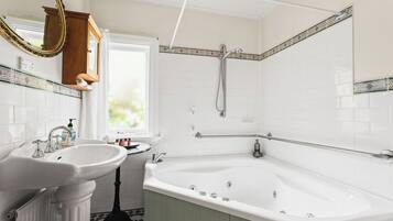 A bathroom with a white sink, a freestanding bathtub, a shower with a handheld showerhead, and a wooden cabinet with a mirror.