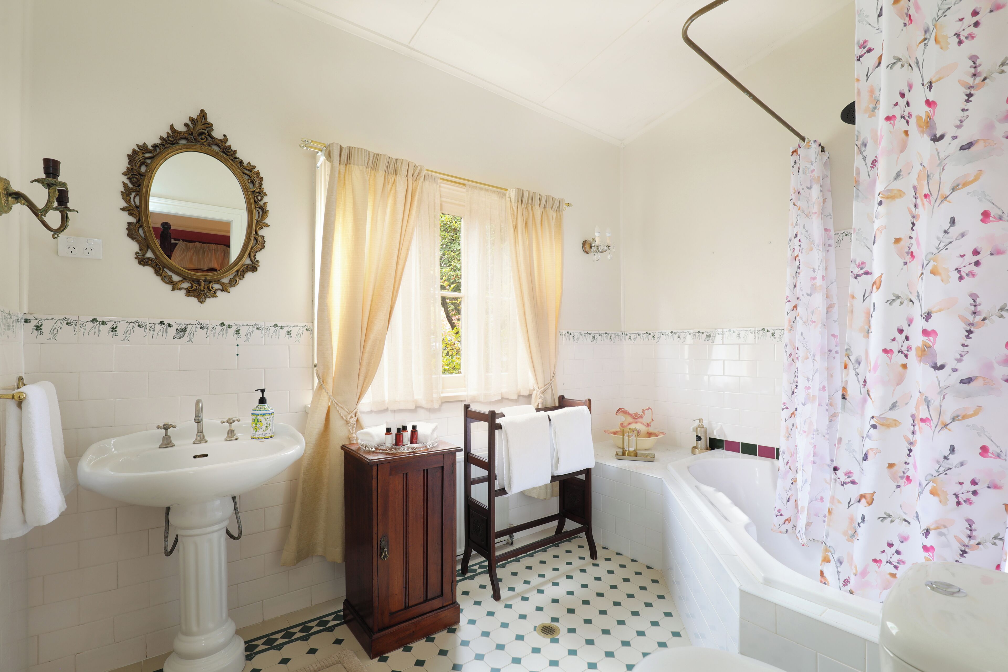 A bathroom with a pedestal sink, vanity, bathtub, and a mirror.