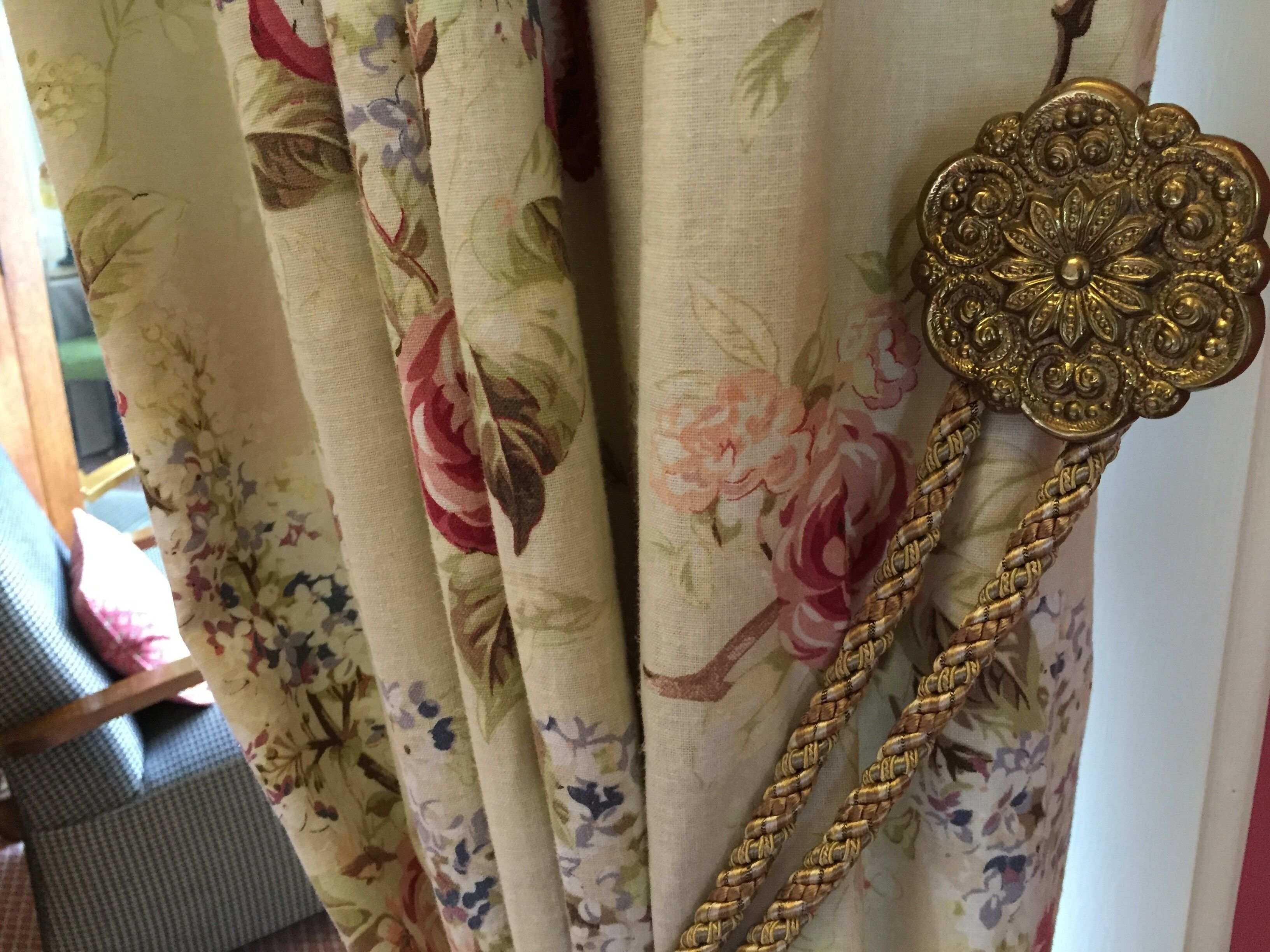 A floral curtain with a decorative brooch.