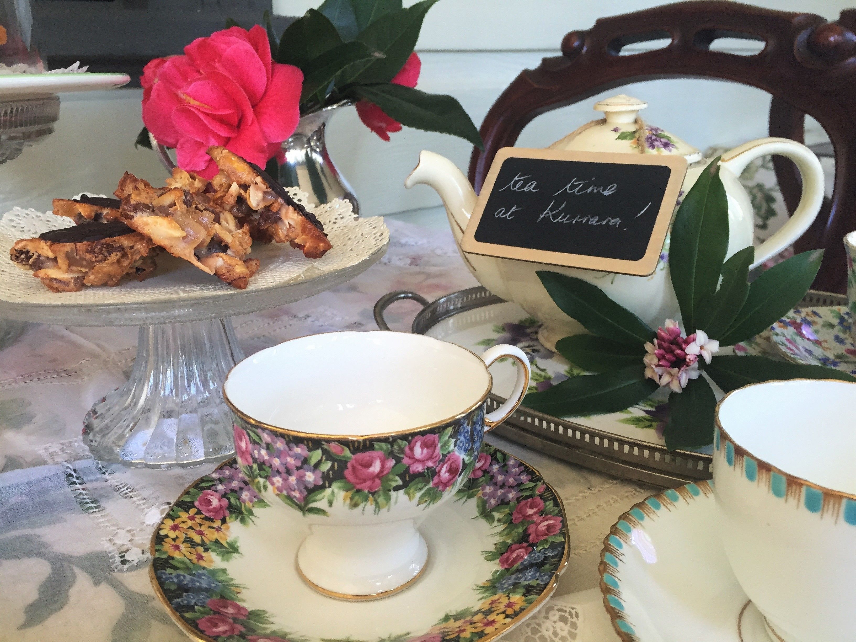 A tea set with floral patterns, a teapot, and a sign that reads "tea time at home."