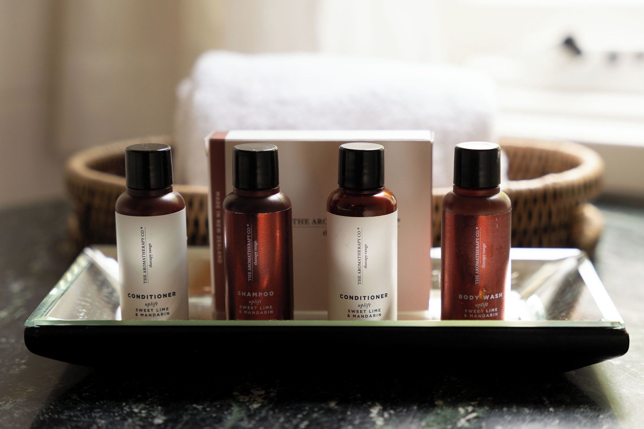 Una bandeja con cuatro botellas de productos de The Aromatherapy Co., un cuenco de madera y una caja blanca.