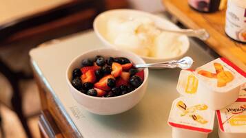 A breakfast tray with a bowl of mixed berries, a scoop of ice cream, and two containers of yogurt.