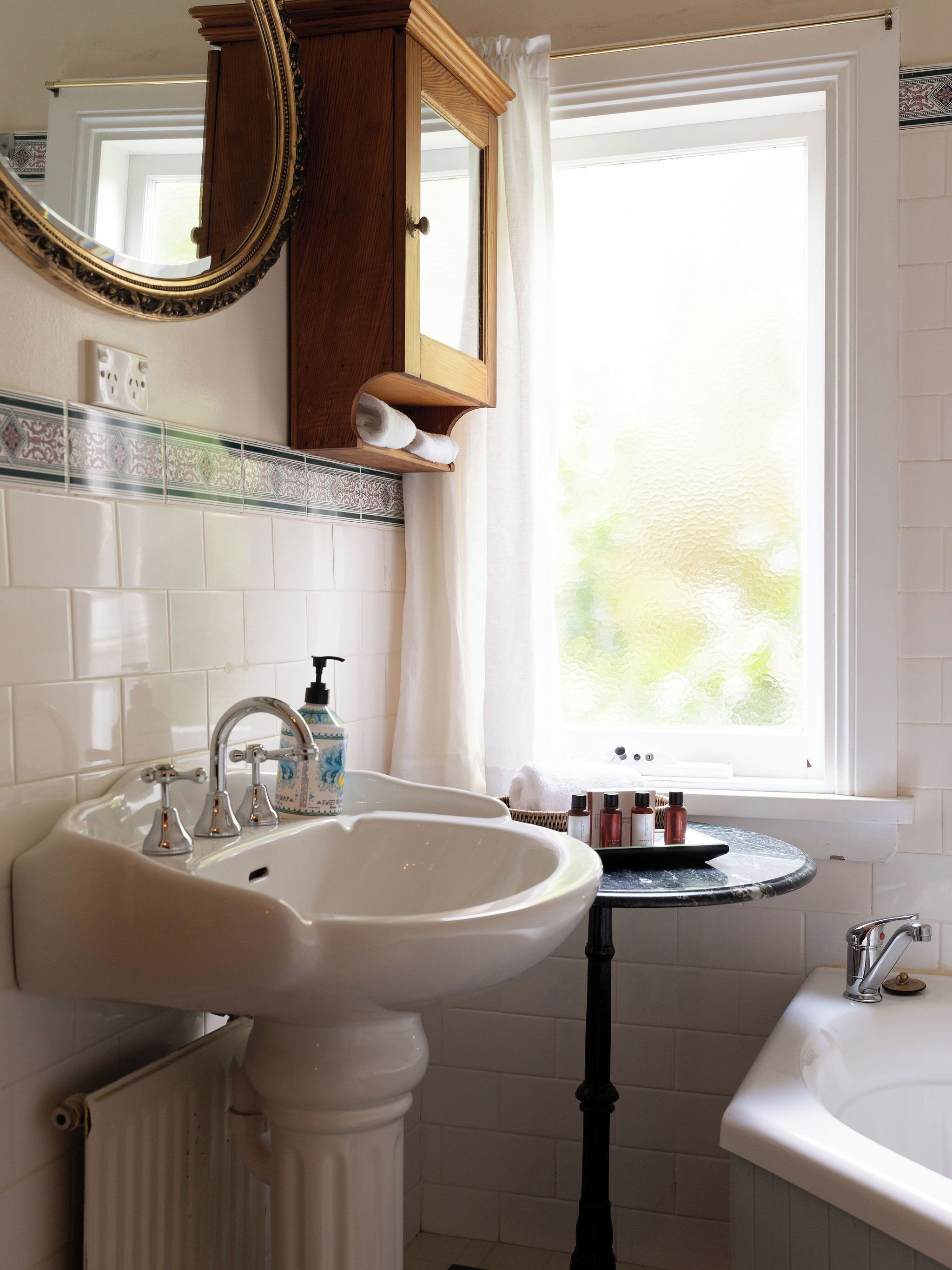 A bathroom with a white sink, a mirror, a window, and a towel rack.