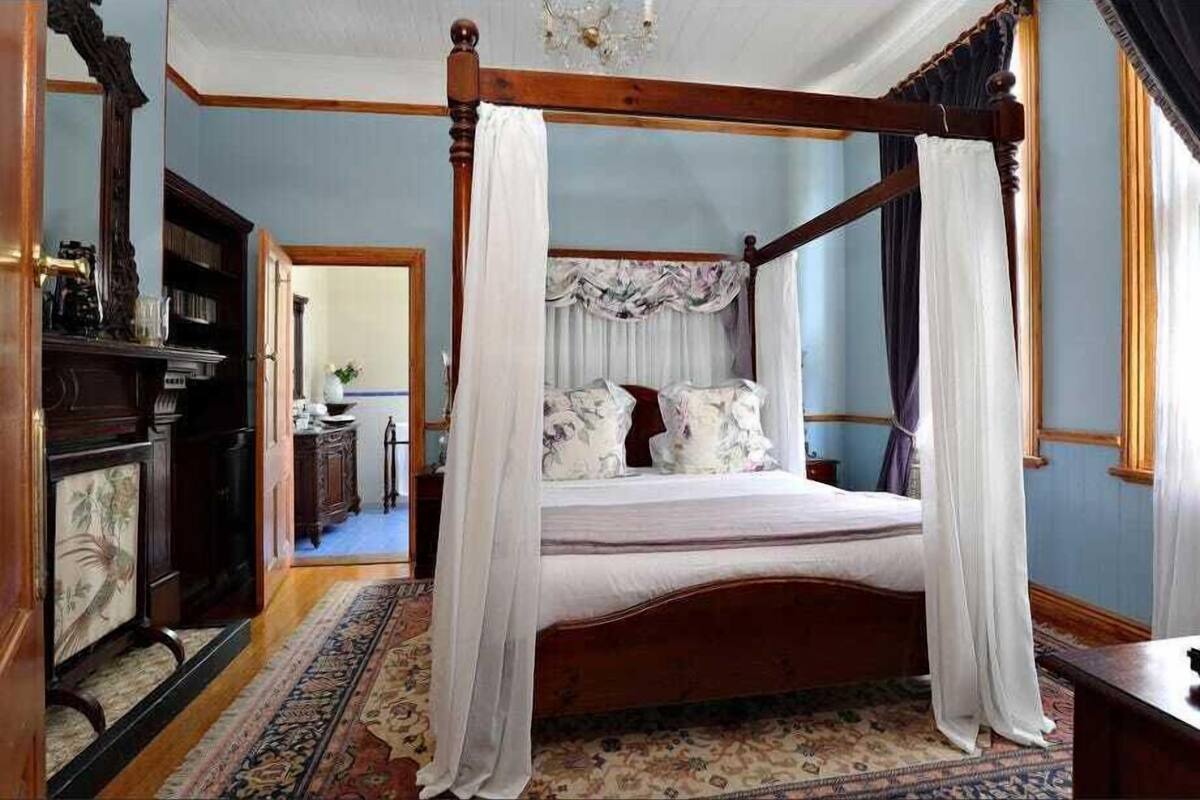 Un lit à baldaquin, un plancher en bois et un tapis à motifs.