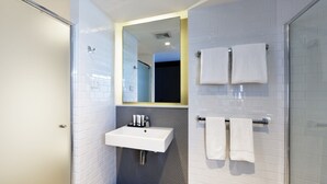 Un baño moderno con un lavabo blanco, un espejo y dos toallas en un perchero.