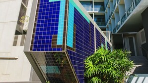 Un edificio moderno con fachada curva, ventanas grandes y una sección con revestimiento de azulejos azules.