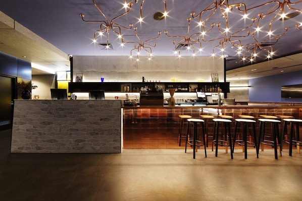 Eine moderne Bar mit einer Steintheke, Barhocker und einer außergewöhnlichen Deckenleuchte.