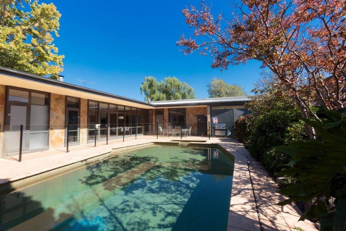 Un bâtiment moderne doté d’une piscine, d’un espace extérieur aménagé et offrant une vue sur un ciel dégagé.